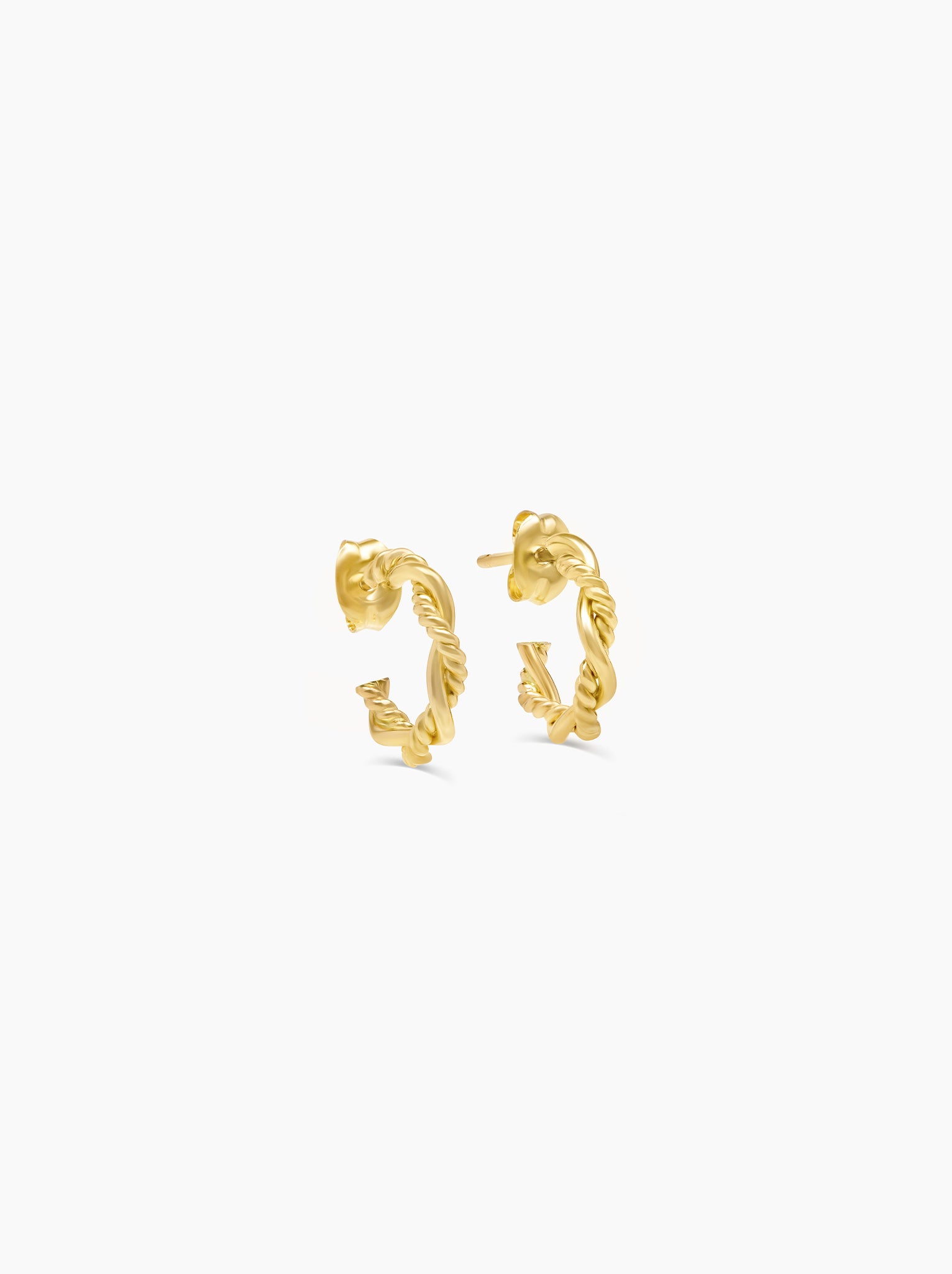 Side angle of a pair of textured braided mini hoop earrings on white background.