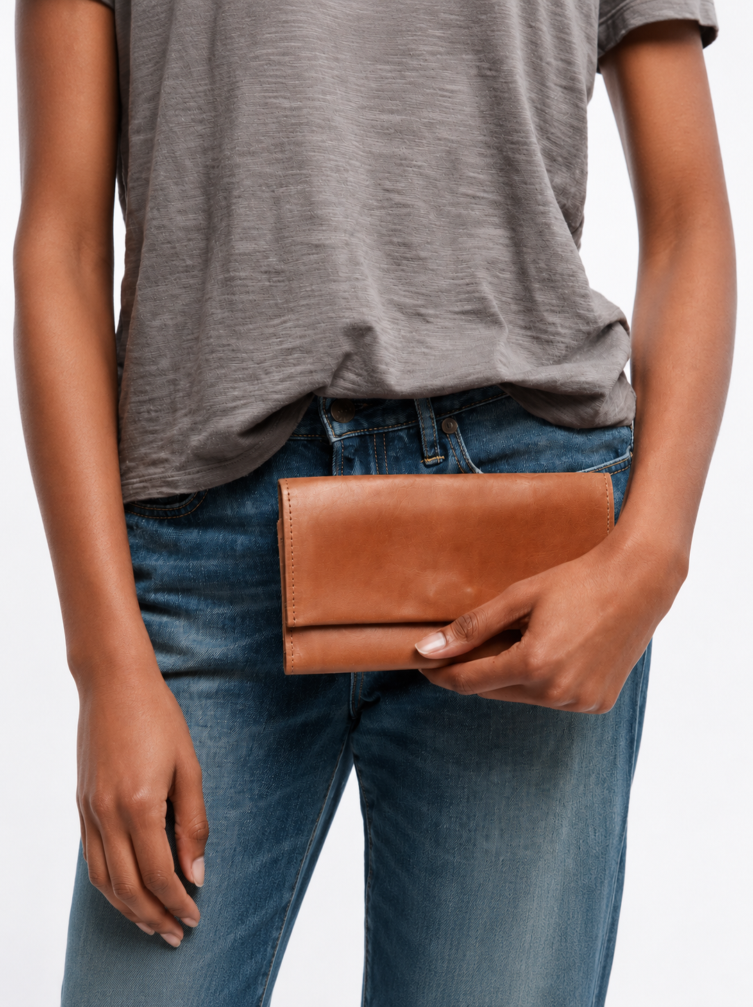 Woman holding closed brown leather wallet in her hand against white background. #Color_Whiskey