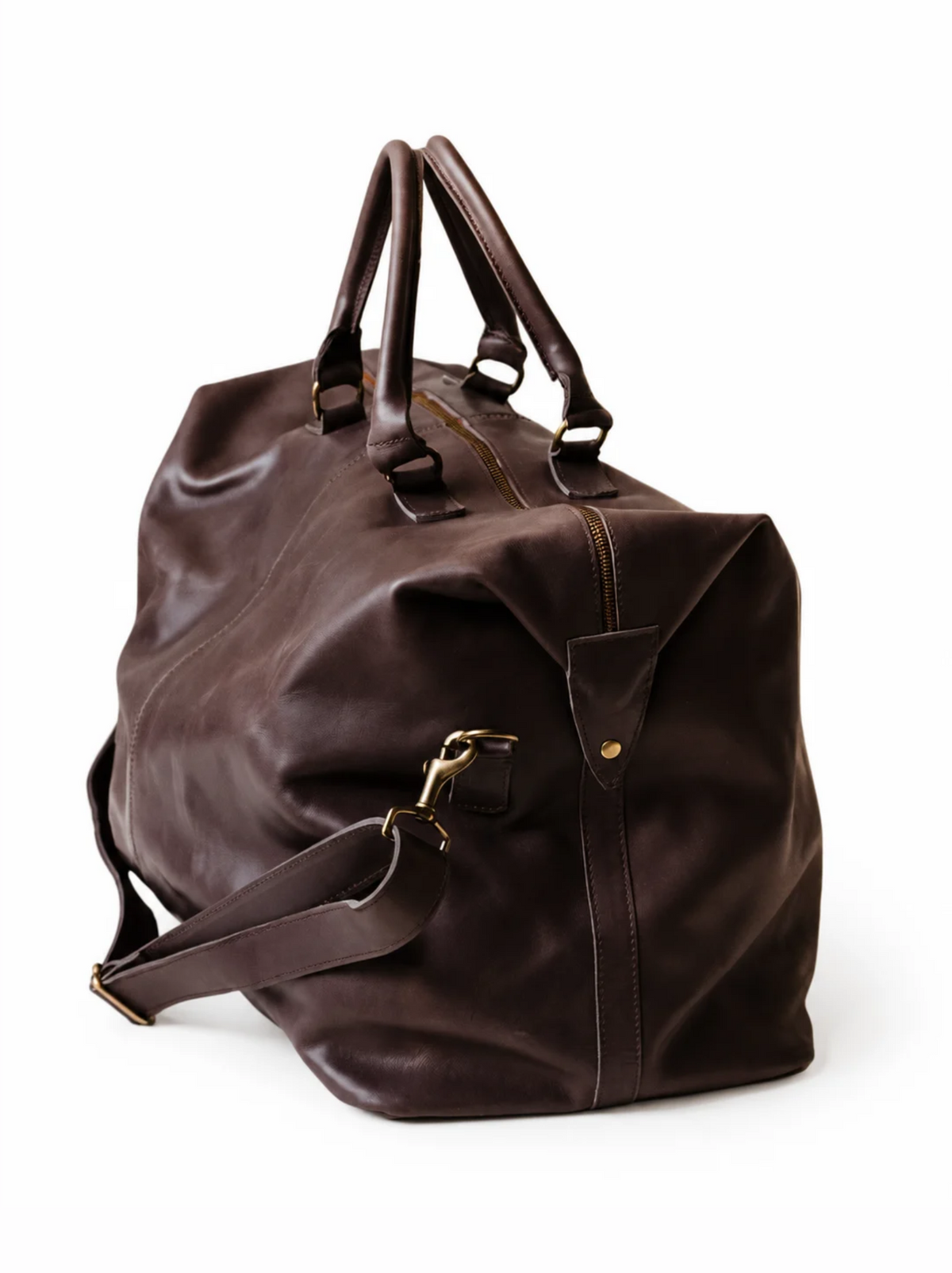 Side view of chocolate brown leather weekender bag, shows side snap, handles and crossbody strap on a white background. #Color_Chocolate Brown