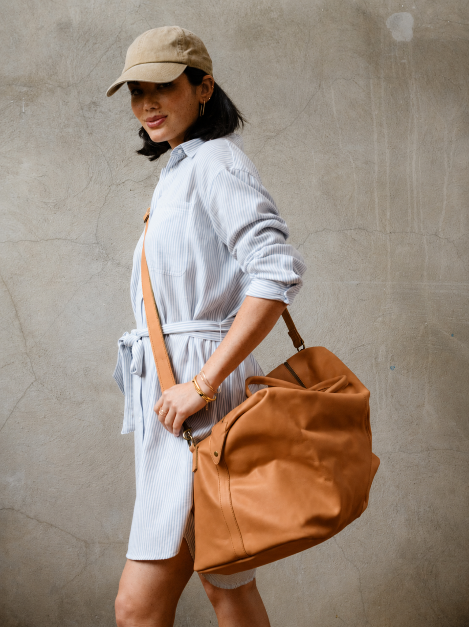 A woman wearing the cognac weekender across her body with the detachable crossbody strap. #Color_Cognac