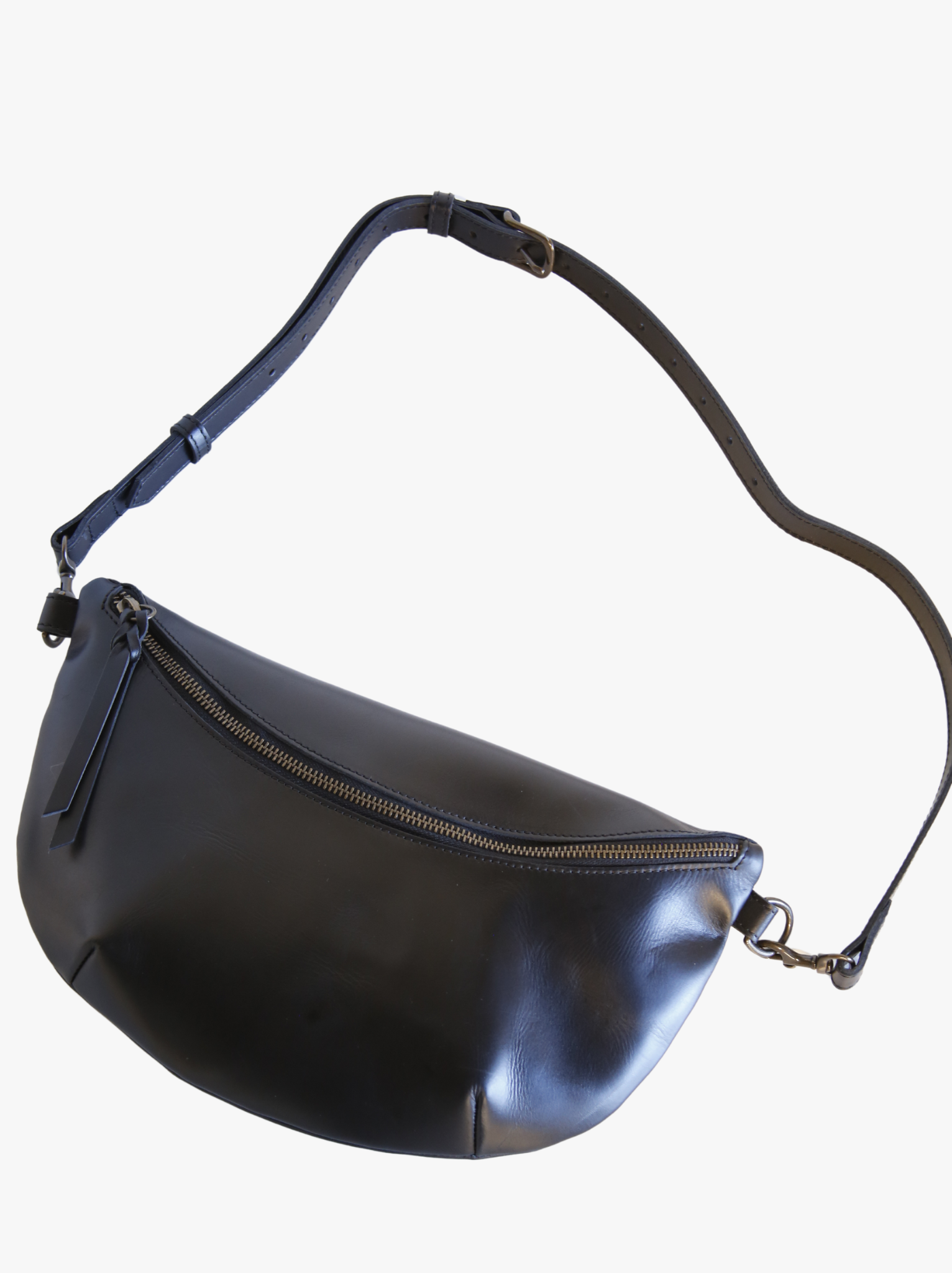 Black leather belt bag with crossbody strap lying out on white background. #Color_Black