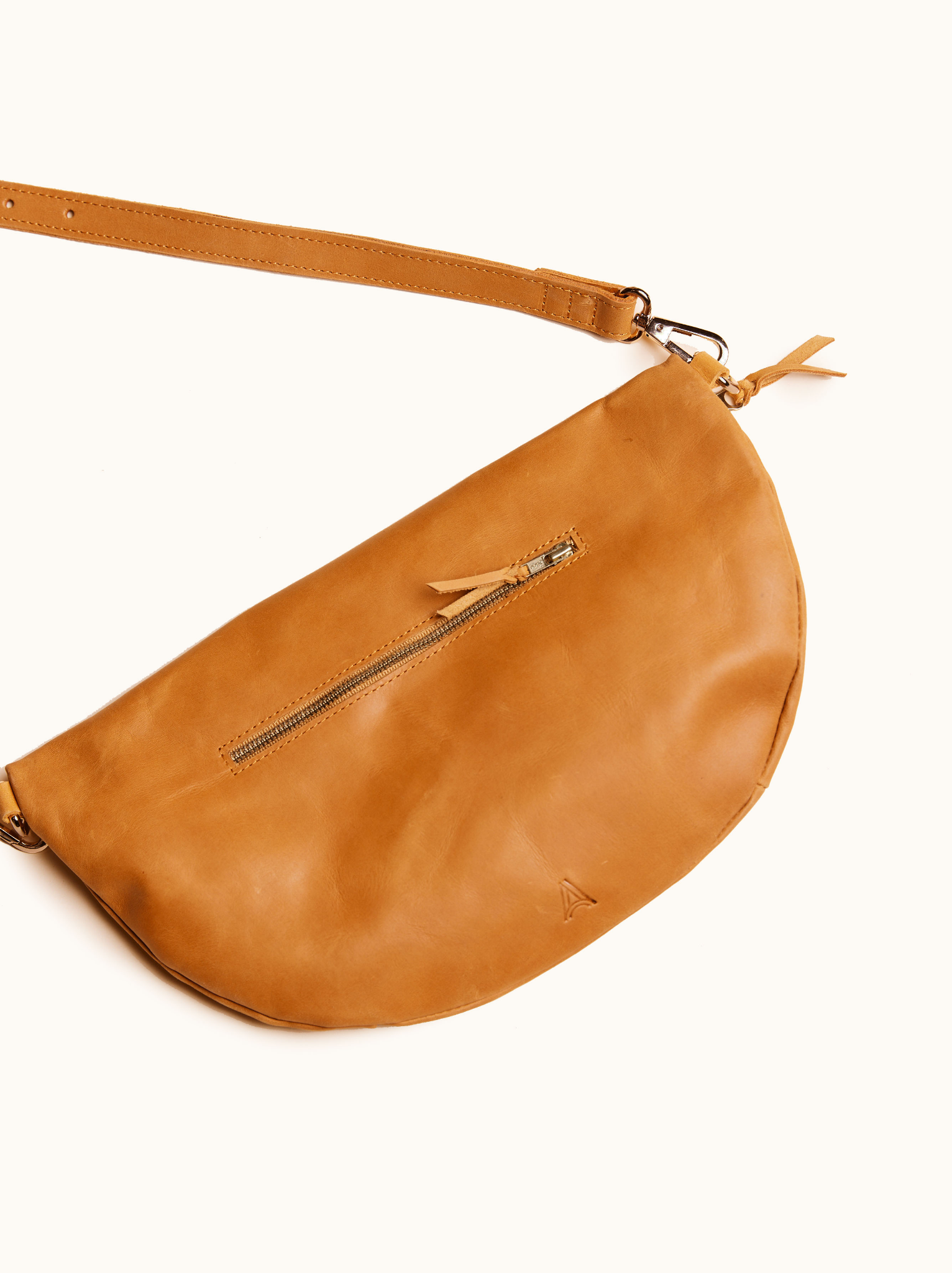 Back of cognac leather belt bag with exterior zipper and brand mark against white background. #Color_Cognac