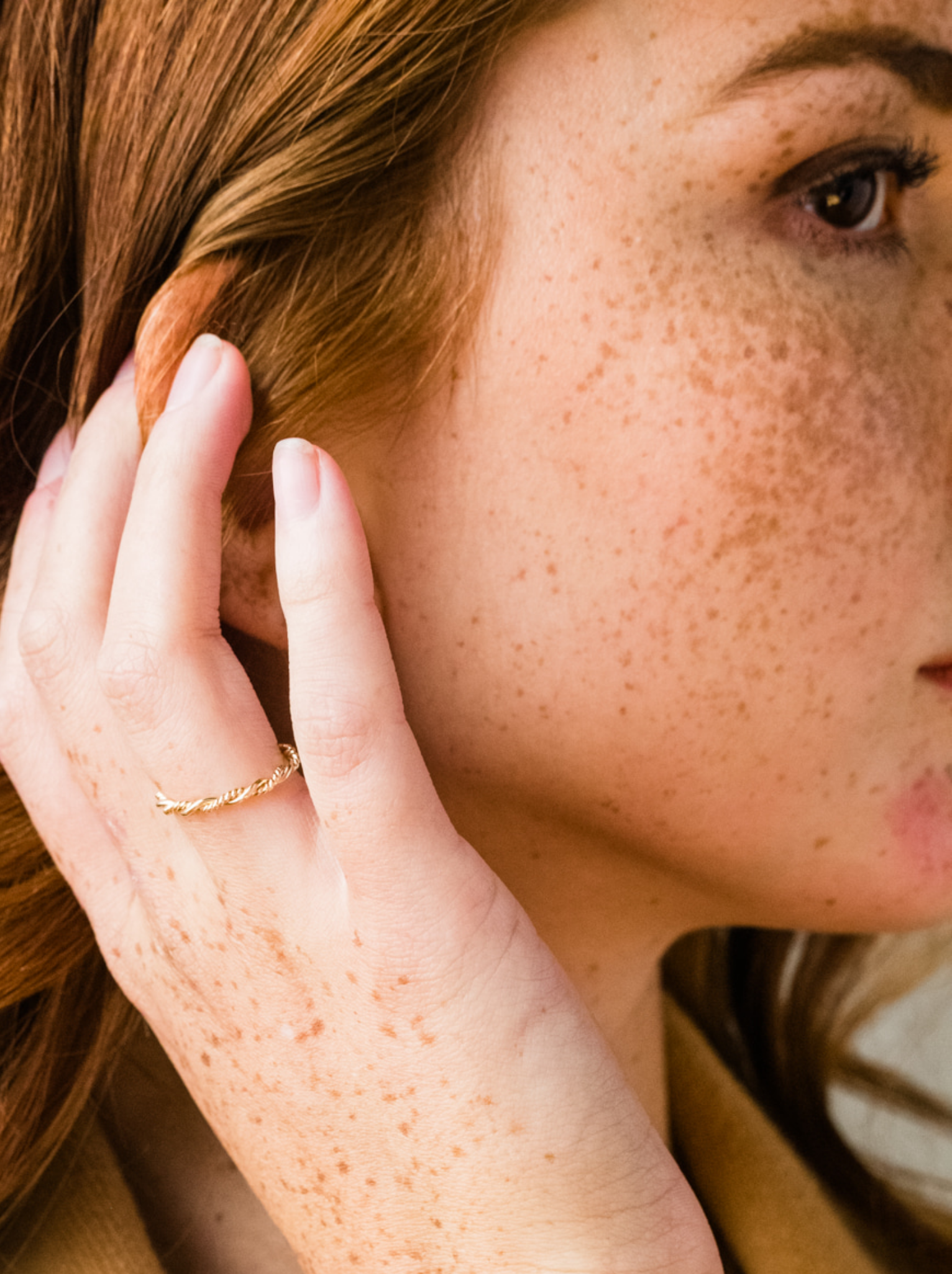 Close up of woman wearing a braided gold ring on right ring finger.
