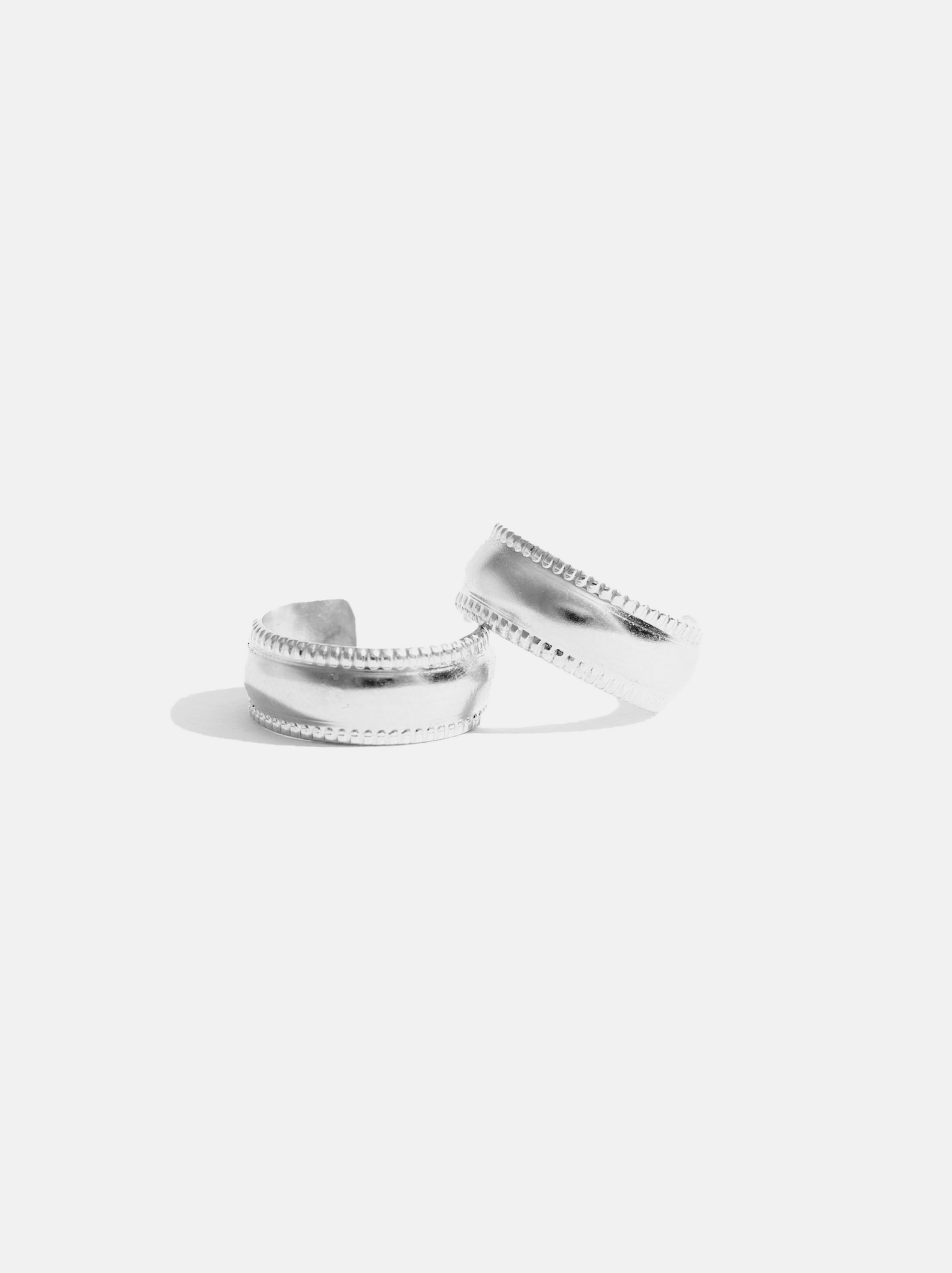 Two silver hoop earrings on top of each other, showing their textured edges on a white background. #Color_Sterling Silver