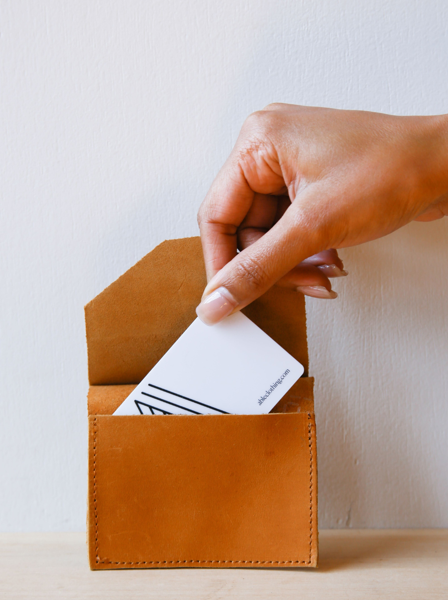Hand holding gift card going into the Lita Leather Envelope cardholder against a neutral background