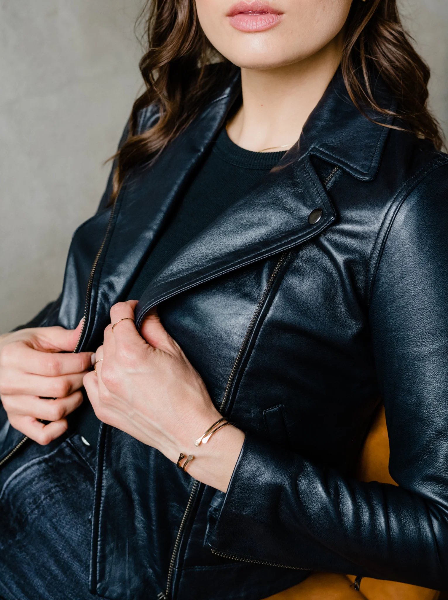 A close up of a woman wearing a black leather jacket. #Color_Black