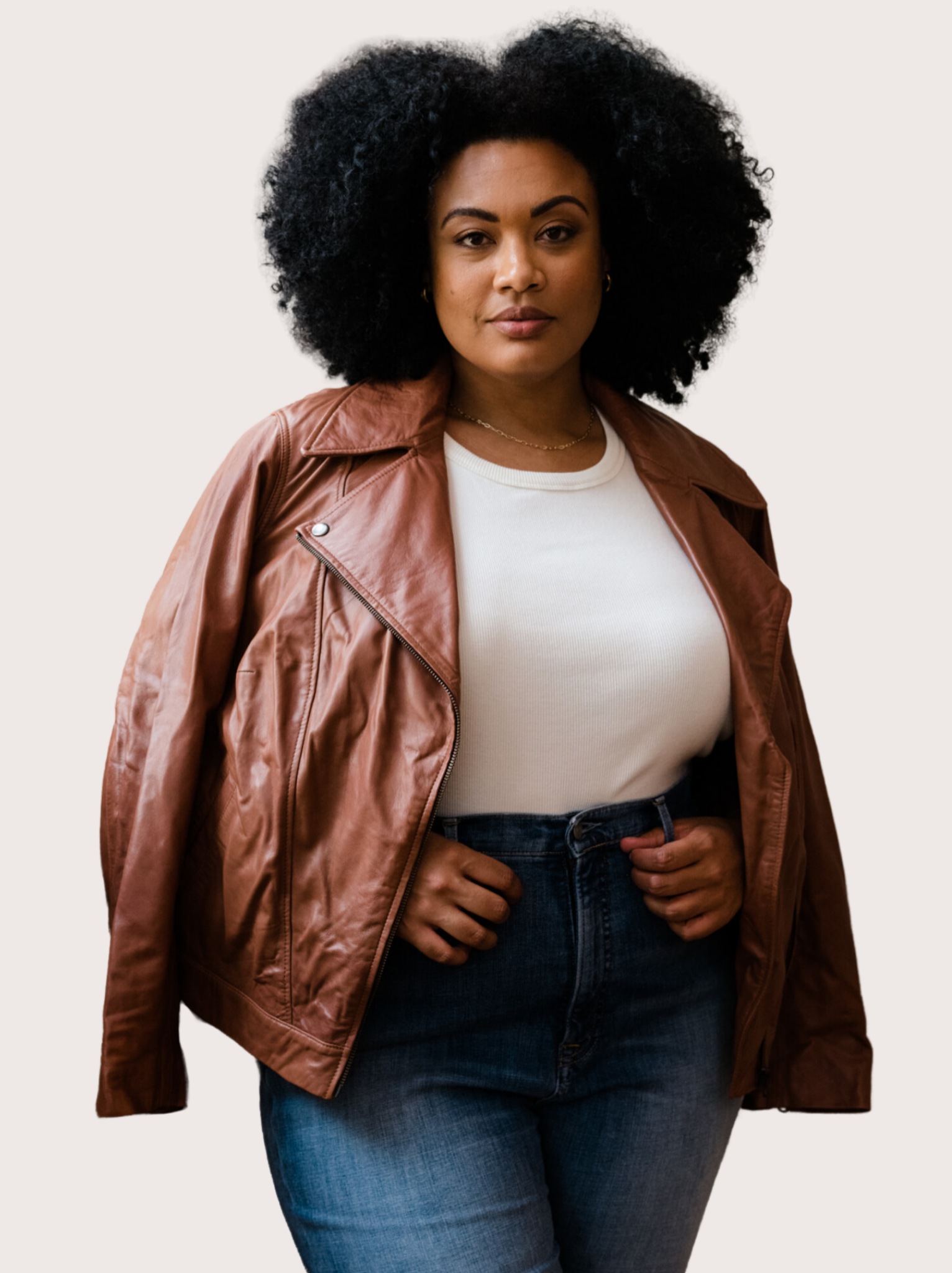 A woman wearing a brown leather jacket on her shoulders with white tank and jeans against white background. #Color_Whiskey