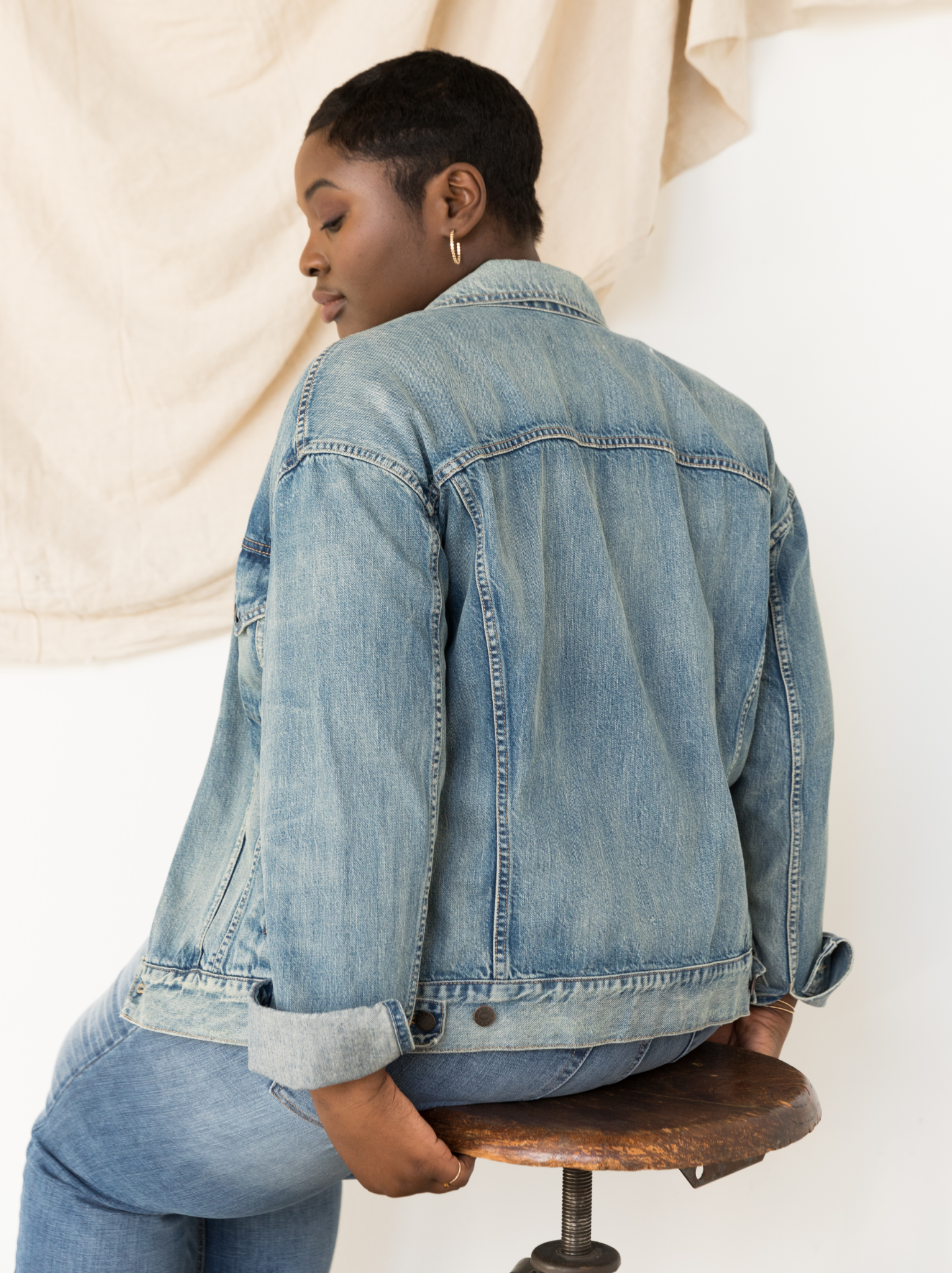 Person wearing The Merly Jacket sitting on a wooden stool against a neutral background #Color_Clean Wash