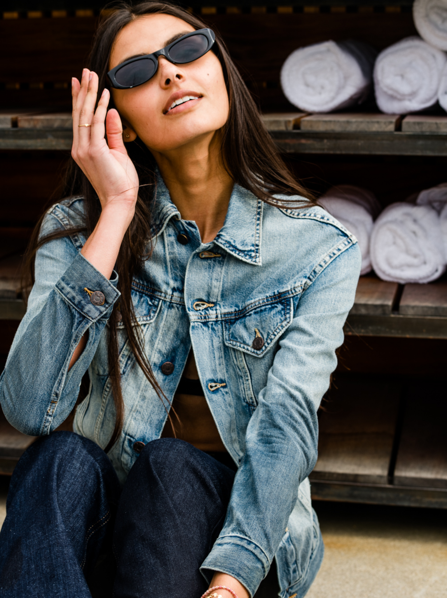 Woman wearing sunglasses and a The Merly Jacket sitting on a bench. #Color_Clean Wash