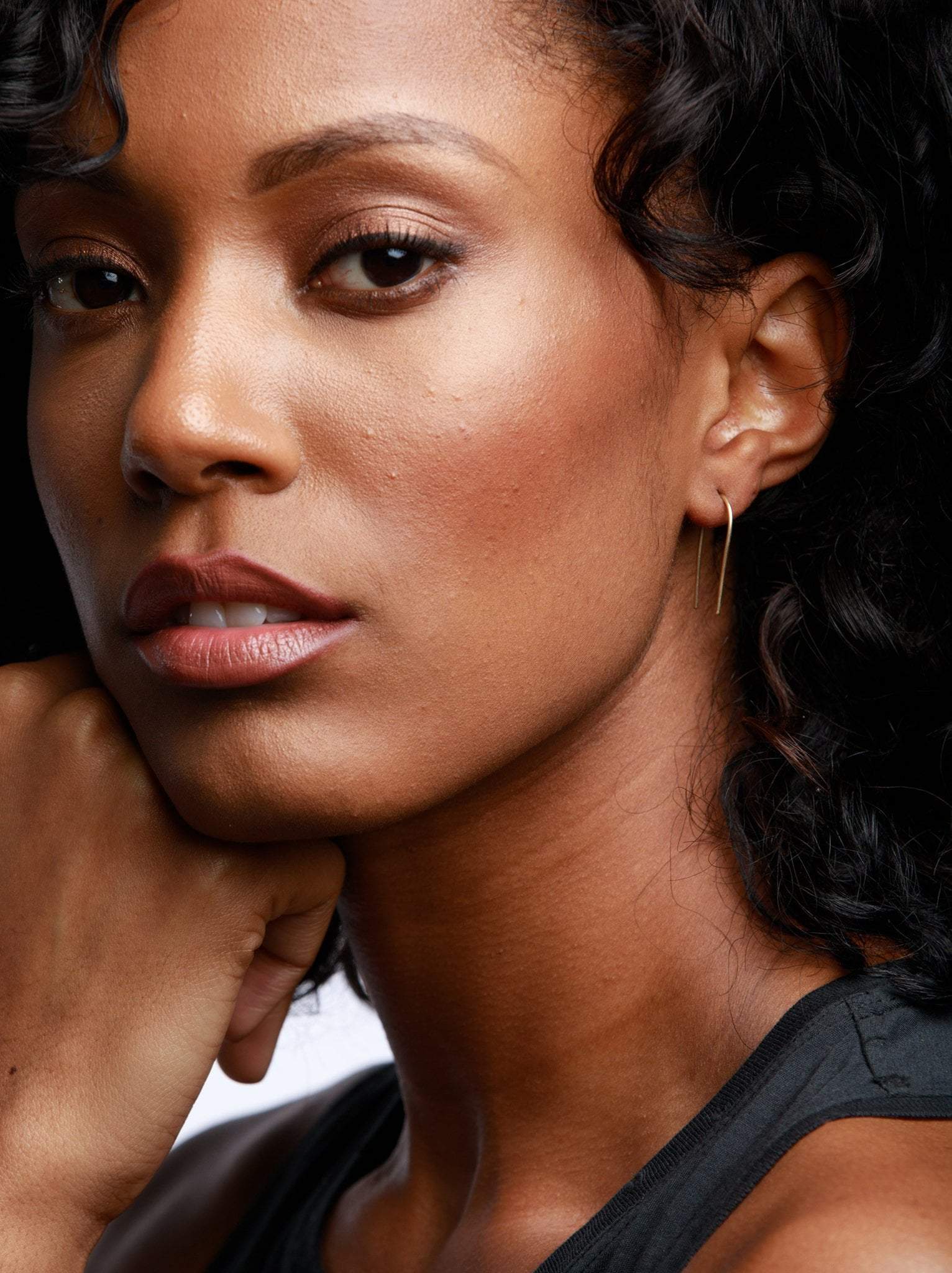 Woman wearing gold upside down U-shaped, arch, earring.