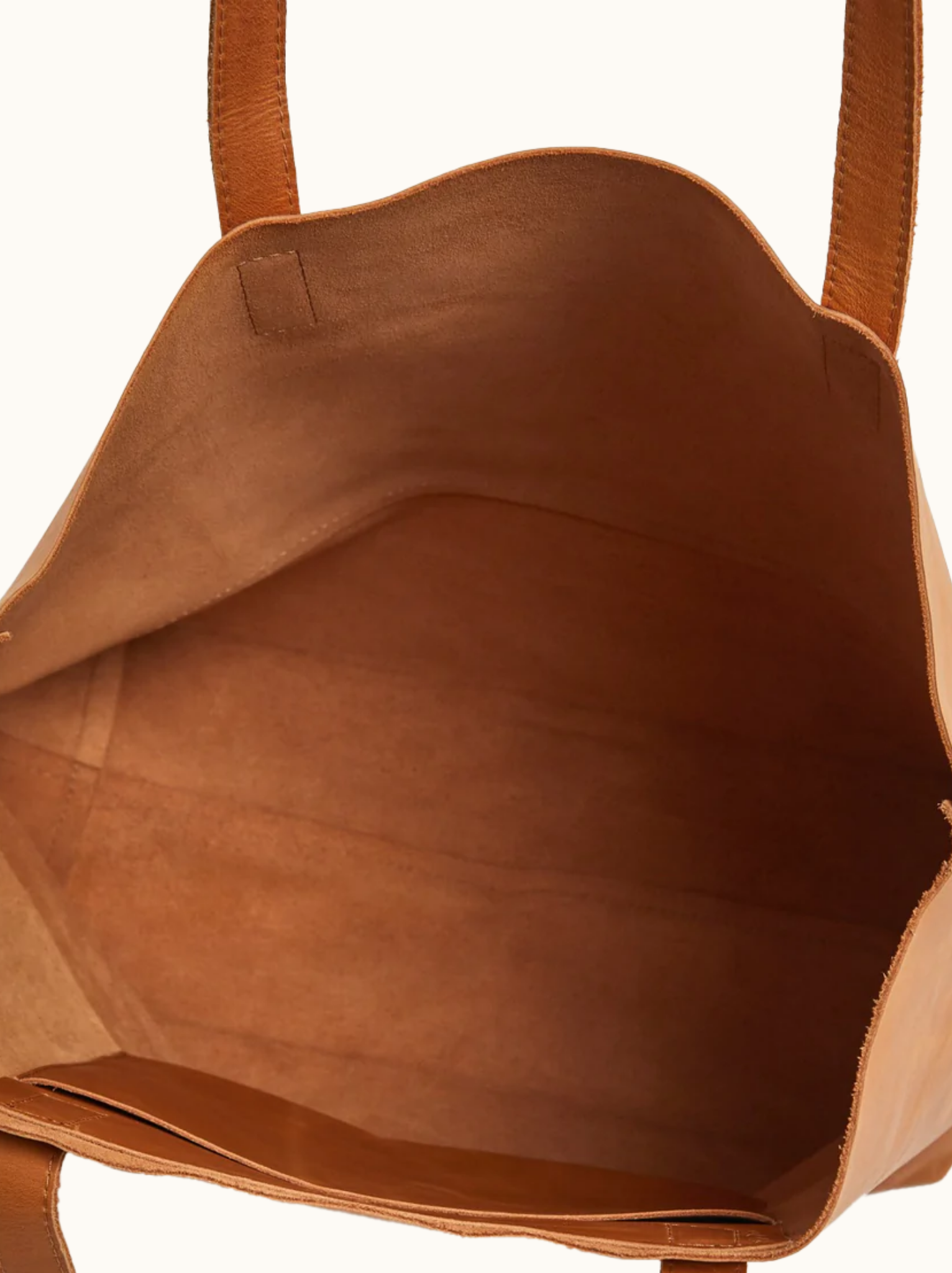 Unlined interior of cognac leather tote with slip pocket against white background. #Color_Cognac