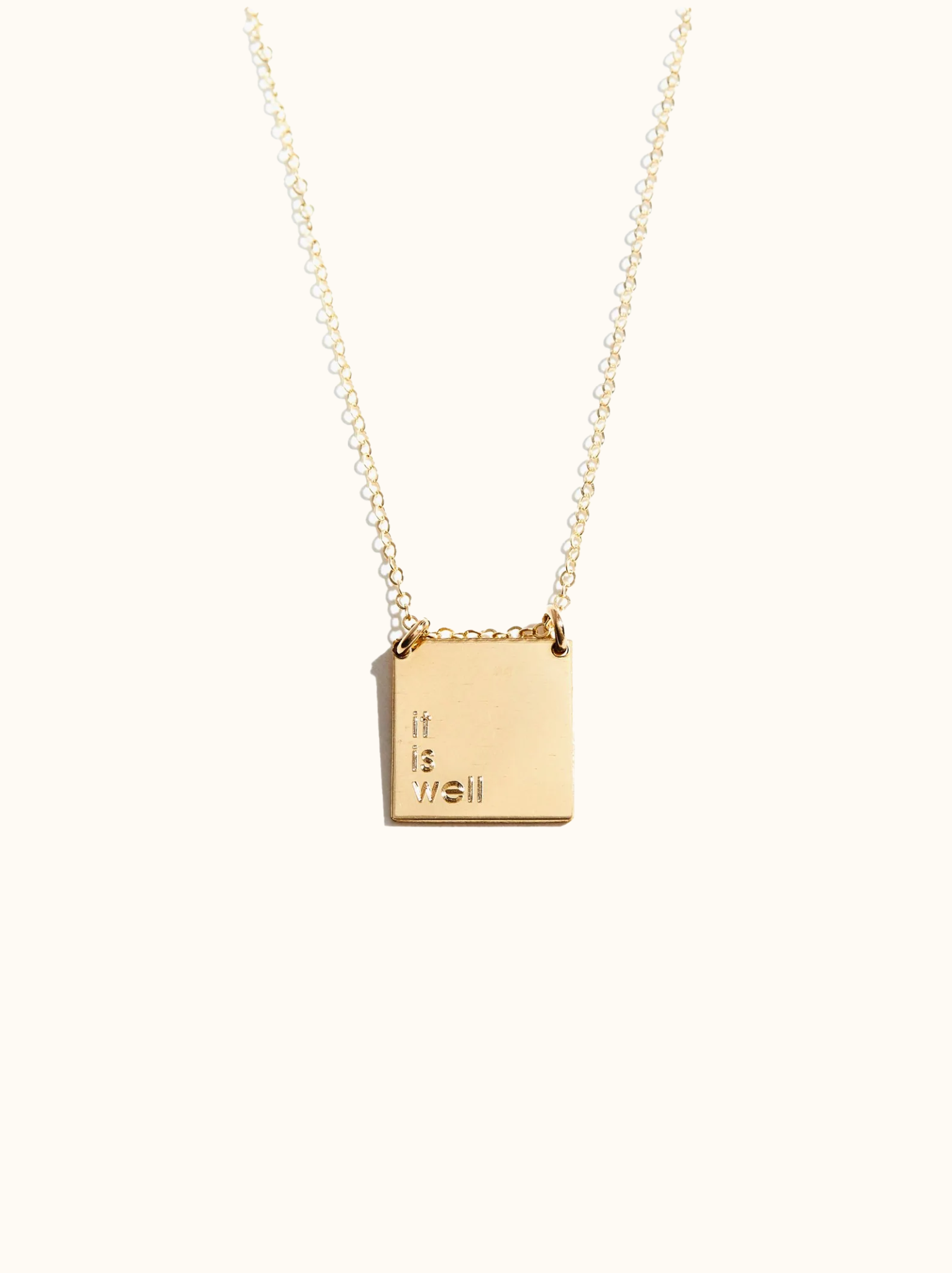 Gold necklace with a square pendant featuring a personalized quote 'it is well' on a white background.