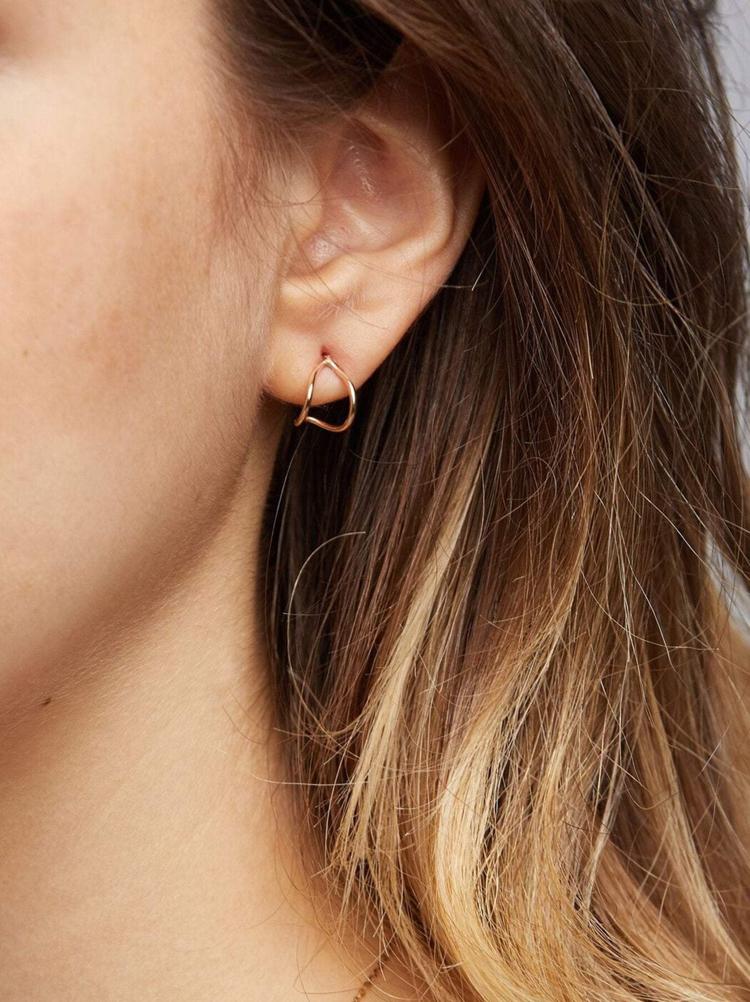 Close up of a woman wearing a gold huggie earring.