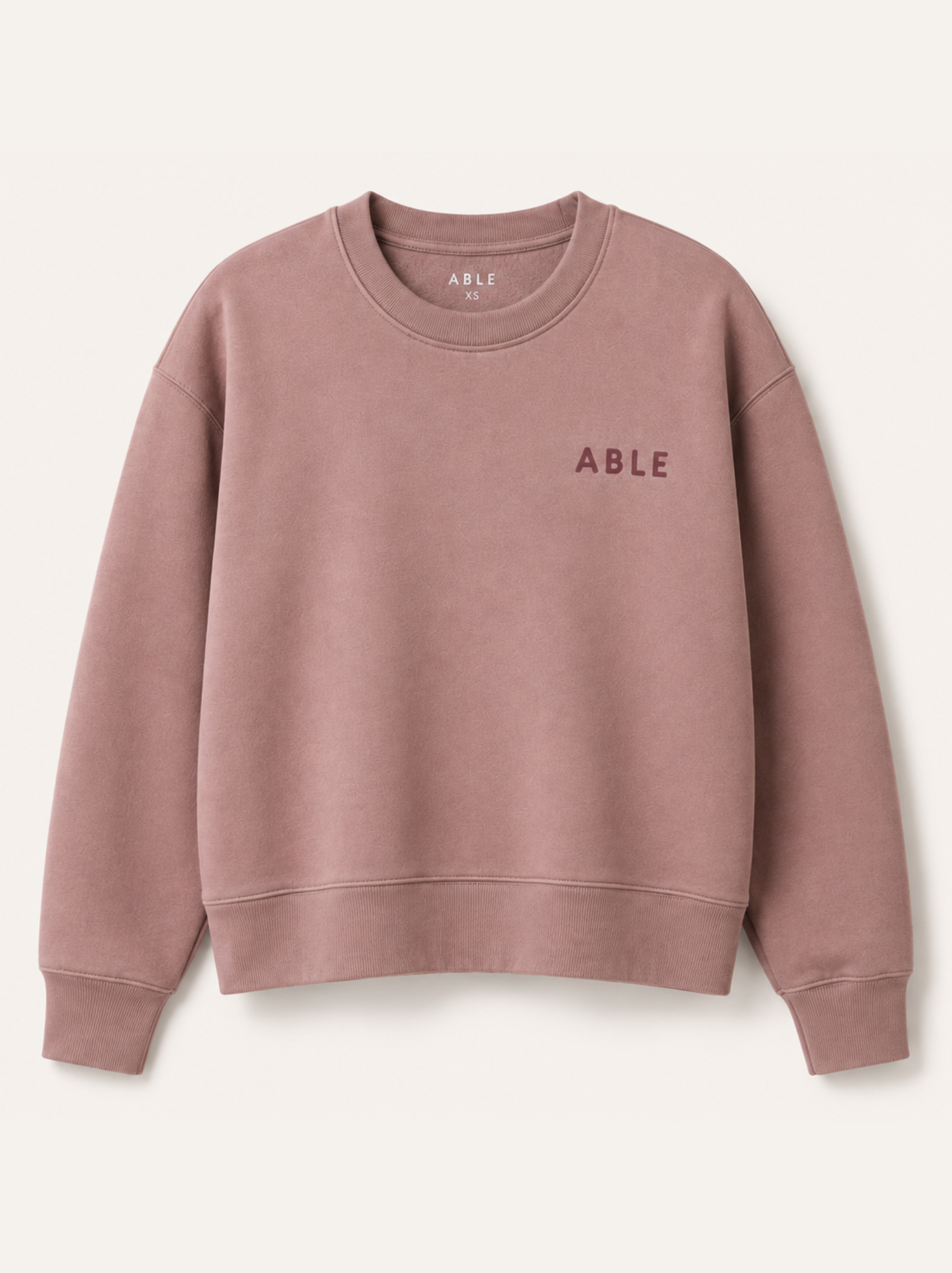 A dusty pink crewneck sweatshirt with 'ABLE' printed in dark pink on the left chest, displayed on a clean off-white background. #Color_Hazel Pink