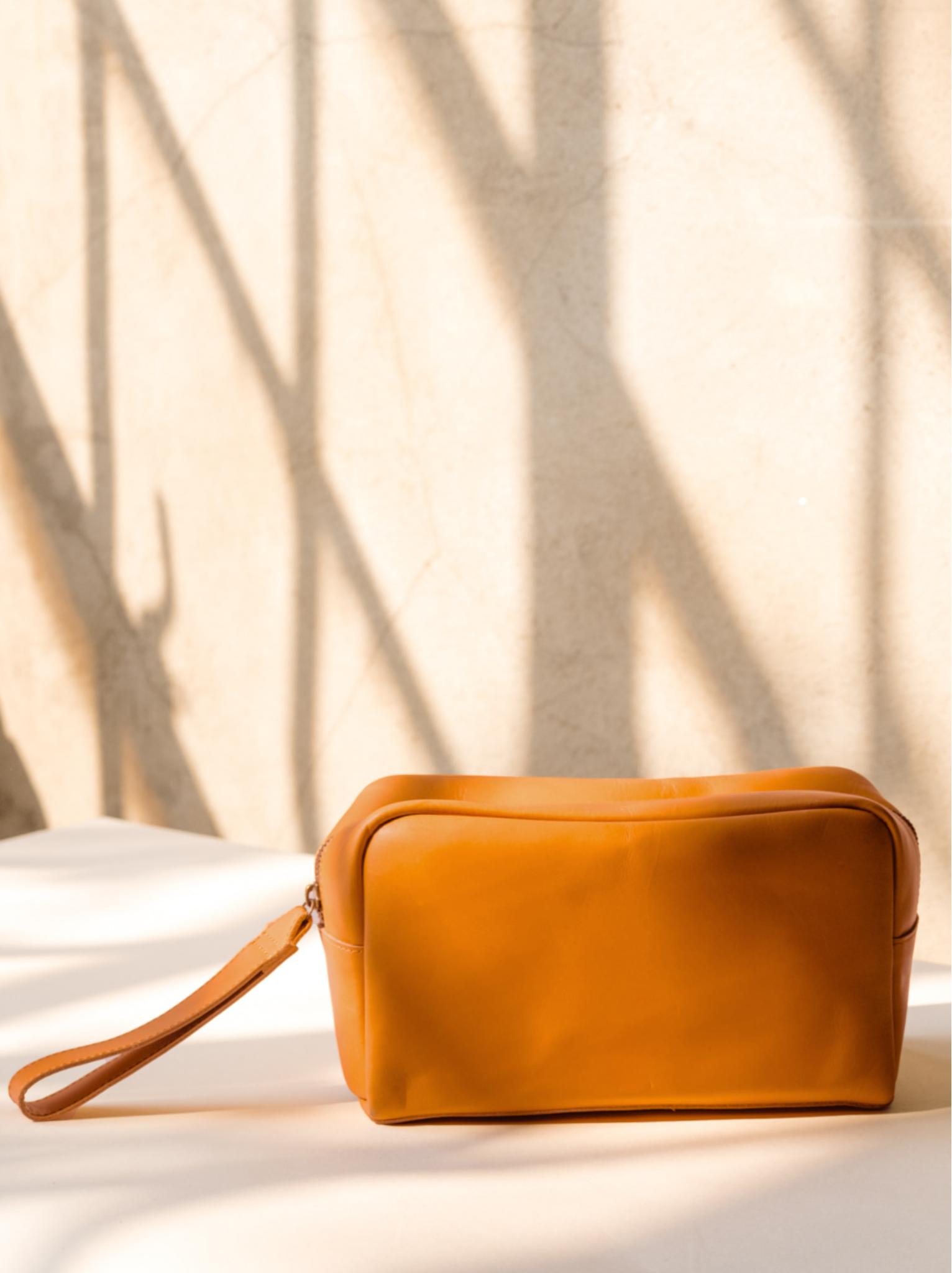 Side profile of Cognac leather dopp kit on a light background. #Color_Cognac