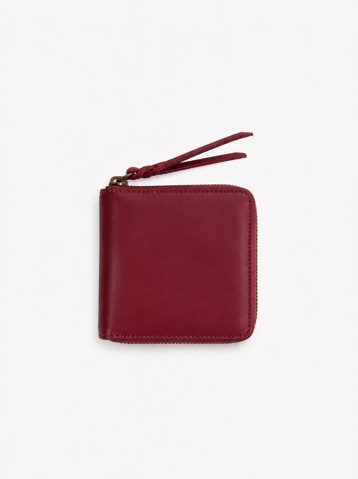 A small red leather zip-around wallet with a matching leather zipper pull and gold-tone zipper , shown on a clean white background. #Color_Oxblood
