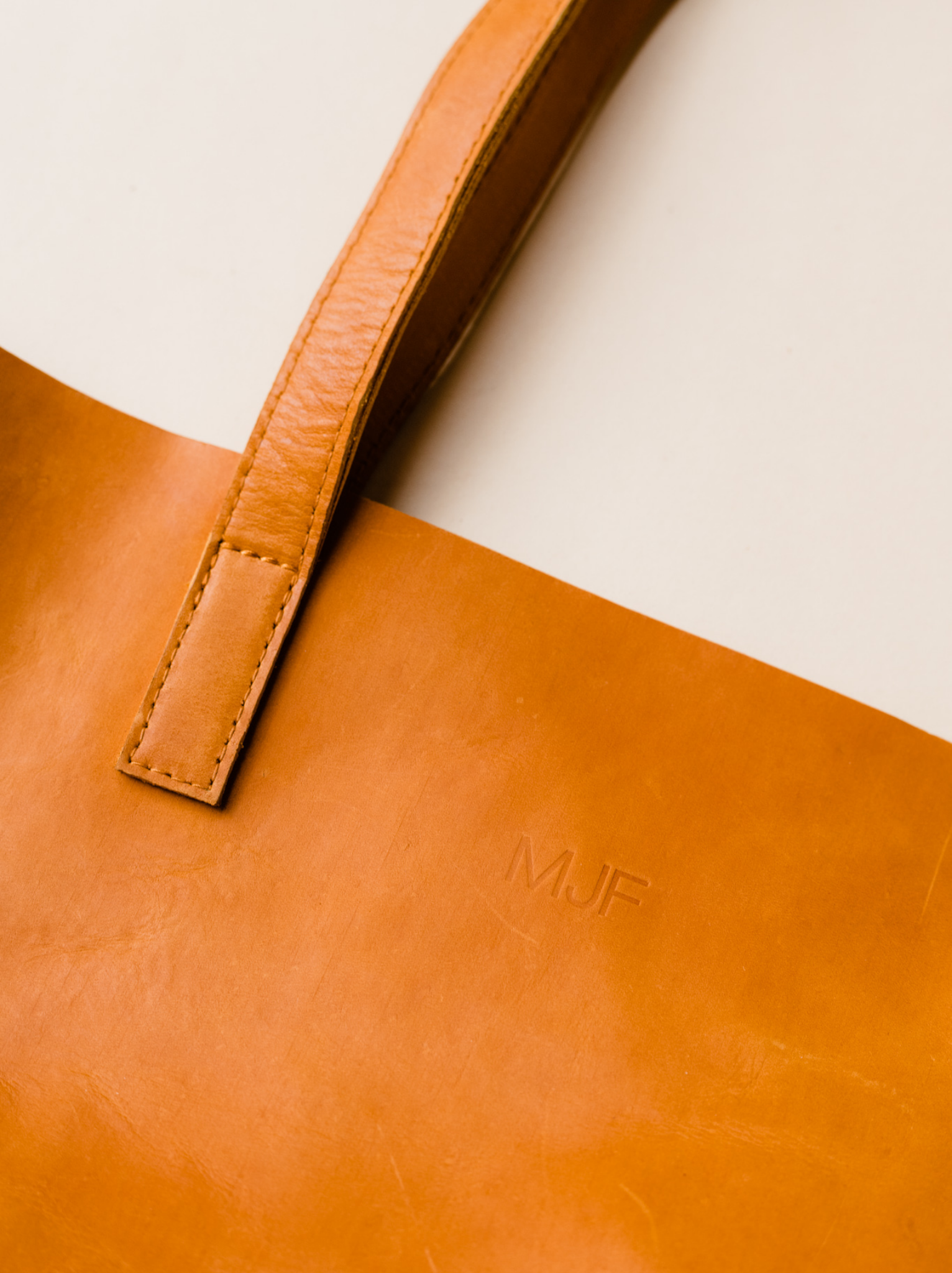 Cognac leather tote with initials from leather debossing on neutral background. #Color_Cognac