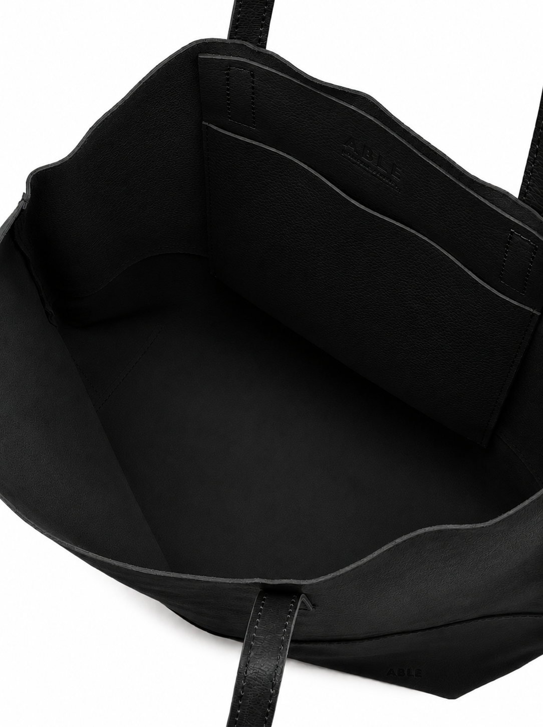 Unlined interior of black pebbled textured tote with one slip pocket on white background. #Color_Pebbled Black