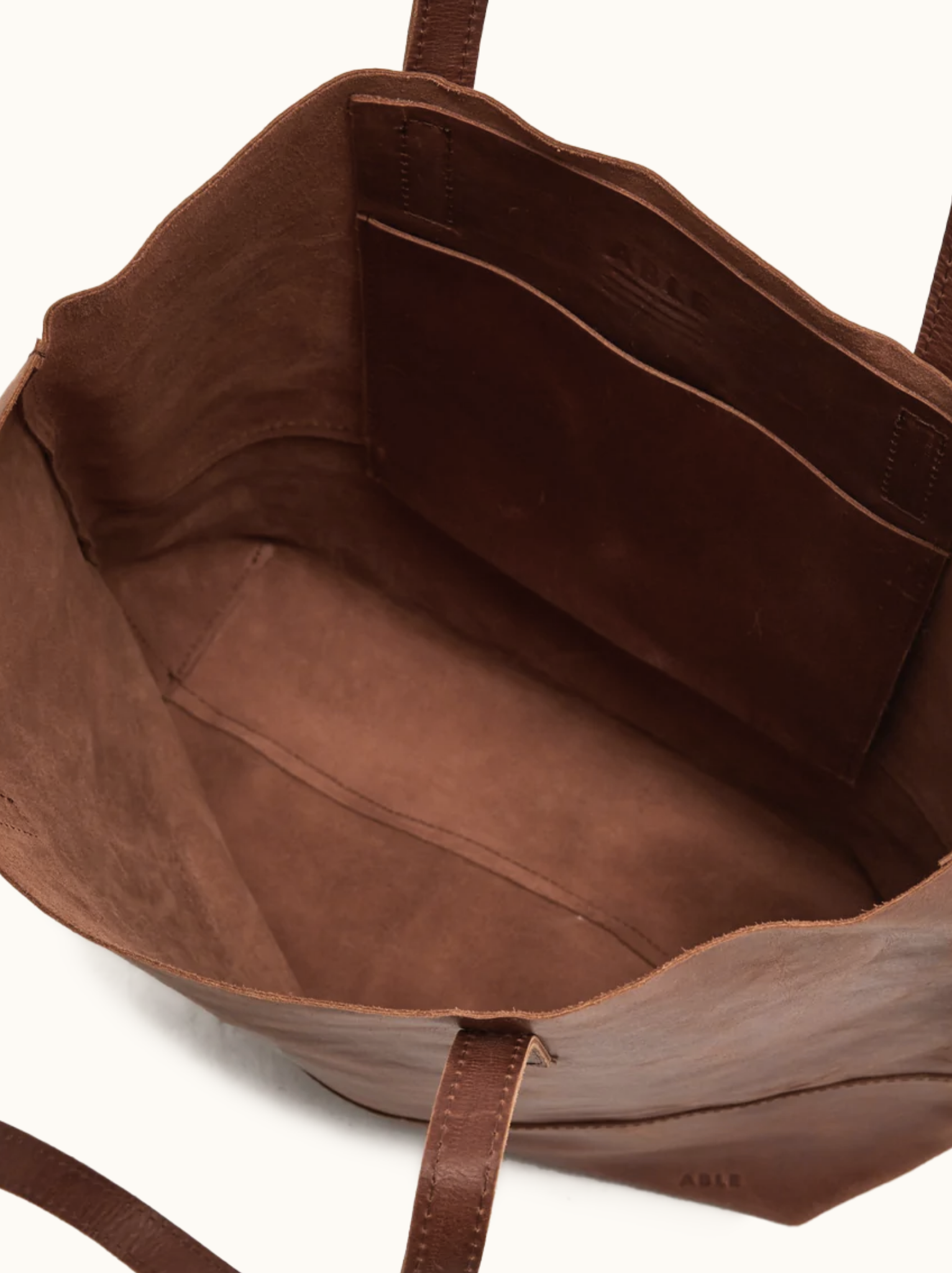 Unlined interior with slip pocket of brown leather tote. #Color_Whiskey