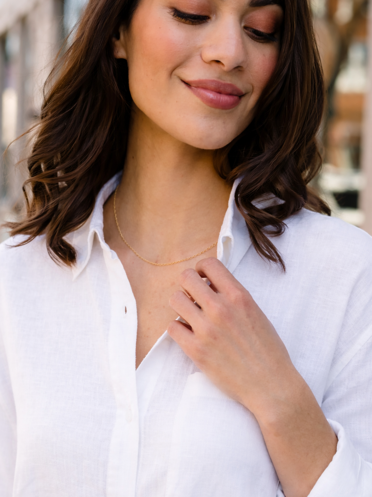 Woman wearing a white shirt and gold necklace outdoors