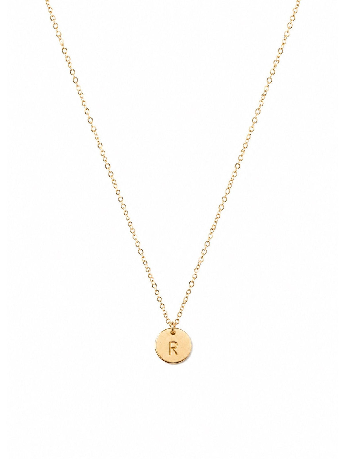 Gold necklace with a round pendant featuring the letter 'R' on a white background.