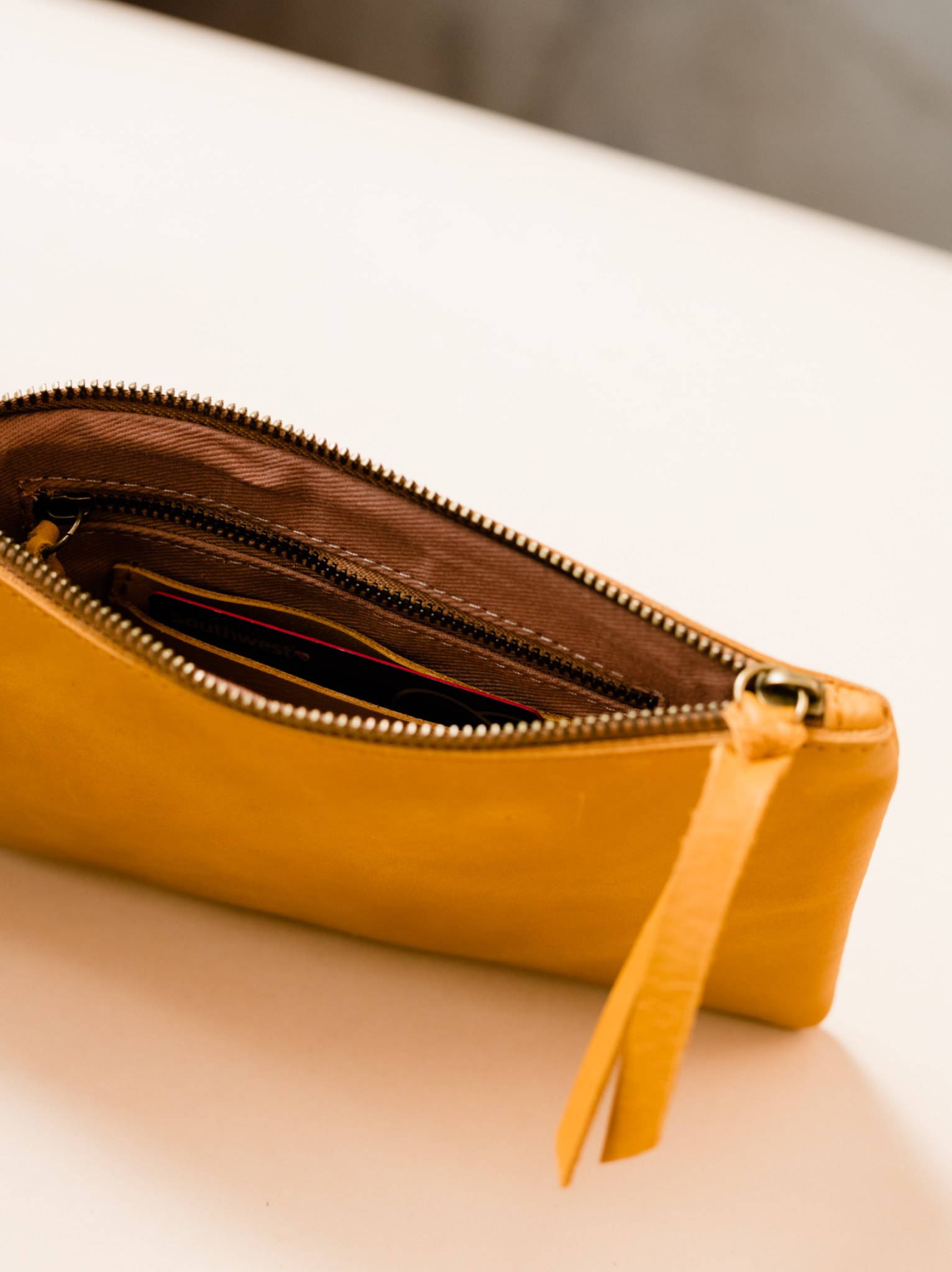Lined interior of orange cognac leather wristlet with zipper pocket and card slots on neutral background. #Color_Cognac