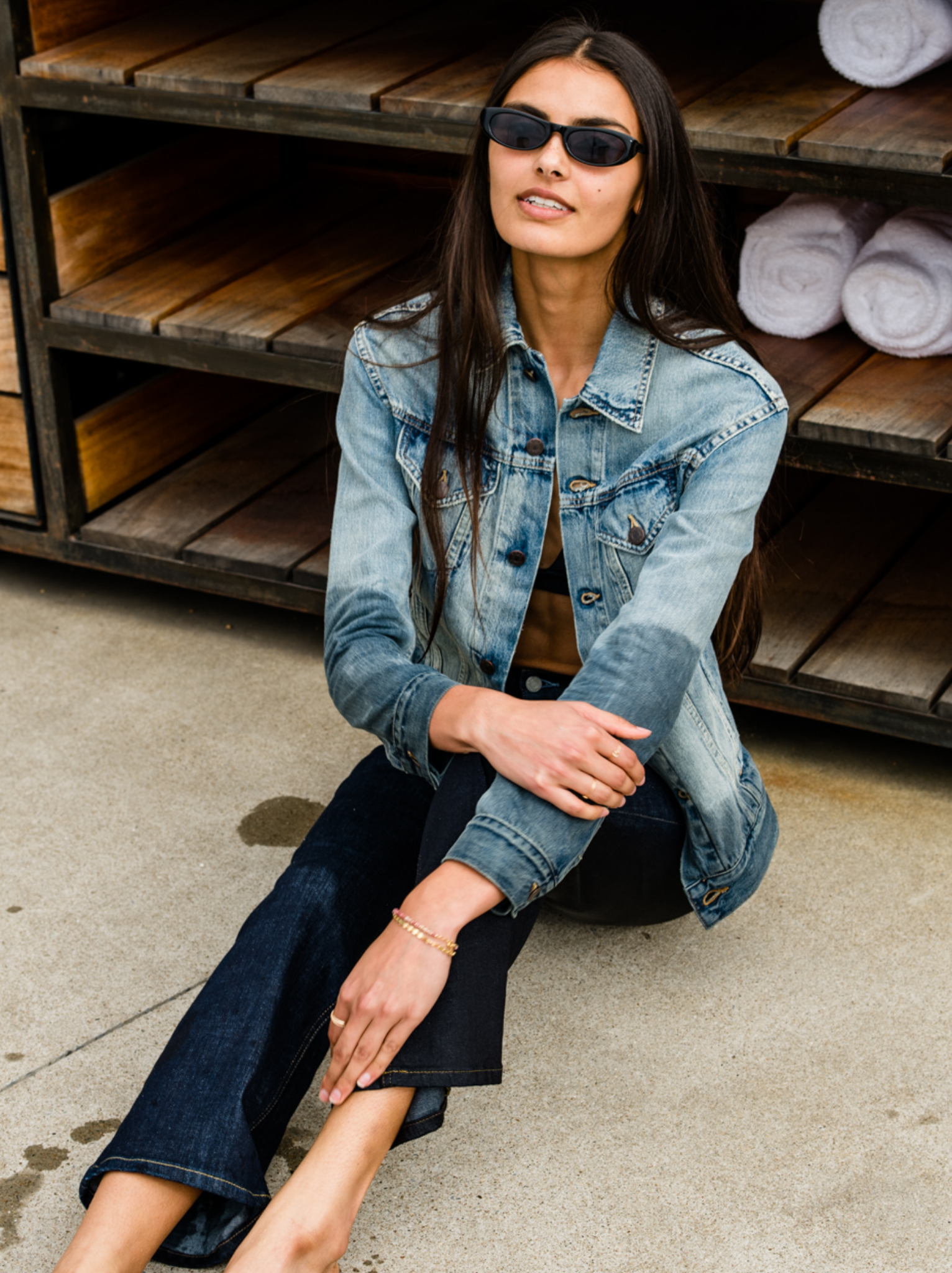 Woman wearing The Merly Jacket sitting on the ground with wooden shelves in the background #Color_Clean Wash