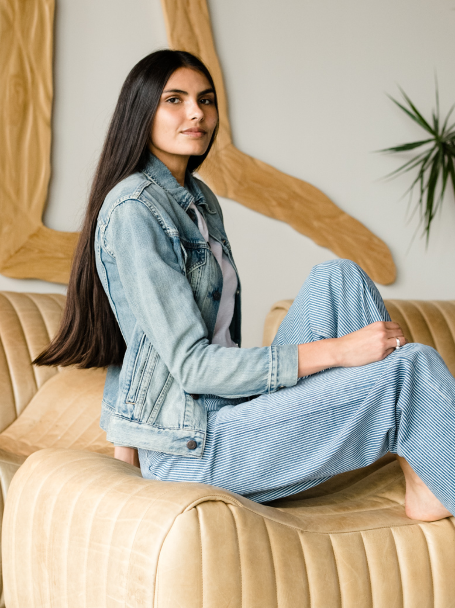 Woman wearing The Merly Jacket sitting on a beige couch. #Color_Clean Wash