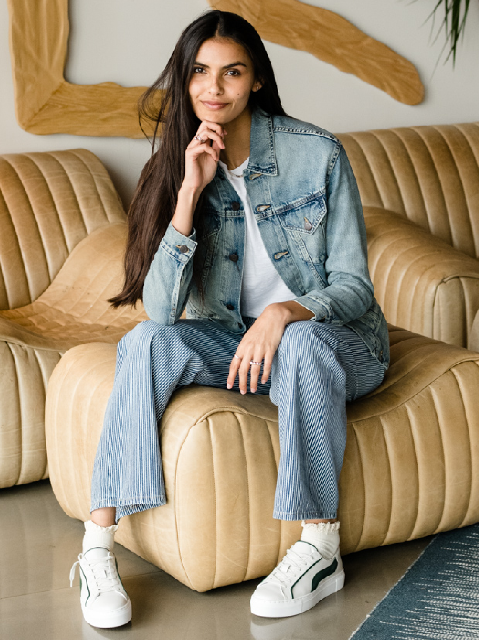 Woman sitting on a beige couch wearing The Merly Jacket and jeans. #Color_Clean Wash